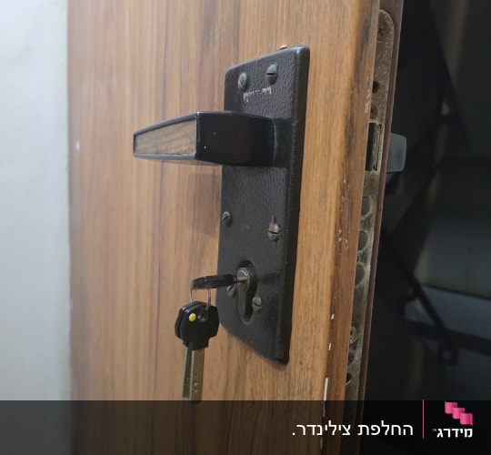 צילינדר ומנעול מותקנים בדלת עץ עם מפתח בחור המנעול